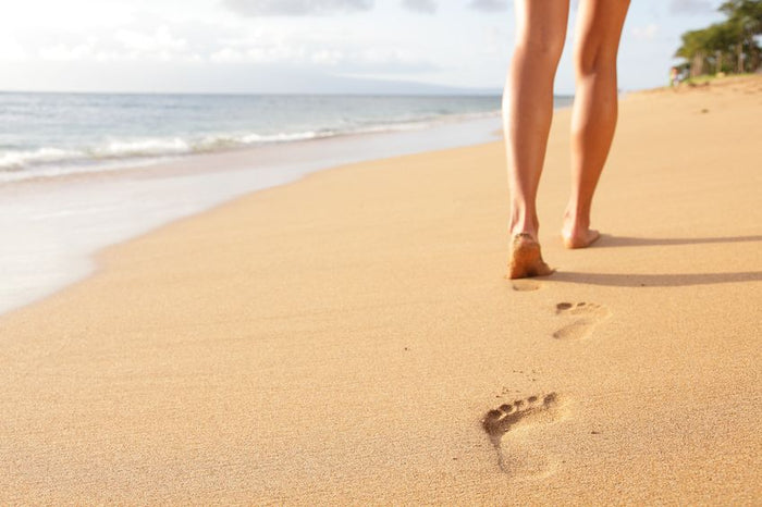 baby foot peel-using woman walking on sand beach leaving footprints in the sand. closeup detail of female feet and golden sand on kaanapali beach, maui, hawaii, usa.