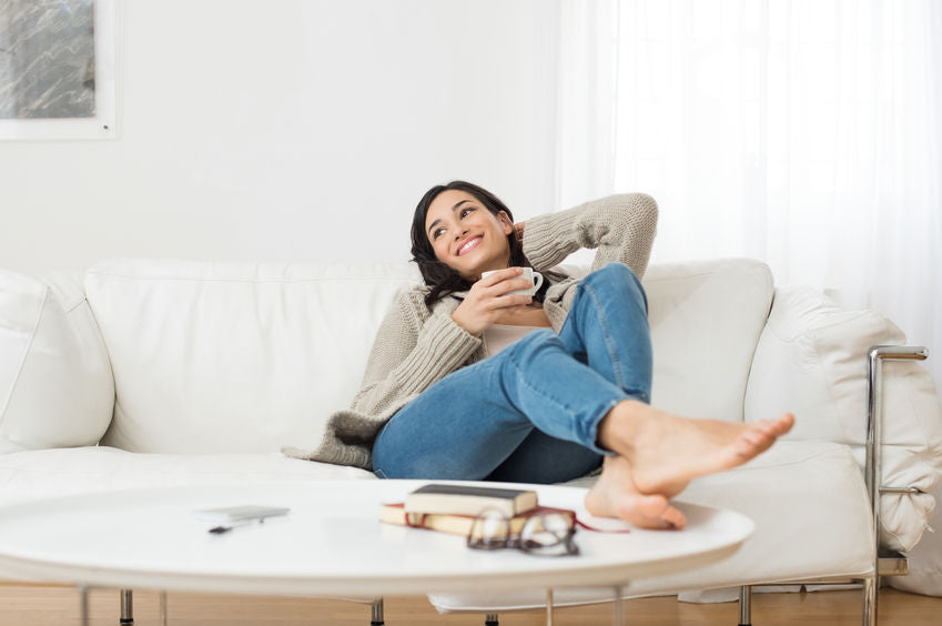 a woman sits happy with her healthy feet from her baby foot moisturizing foot mask