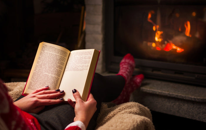 A person reads a book while performing a Baby Foot foot peel treatment