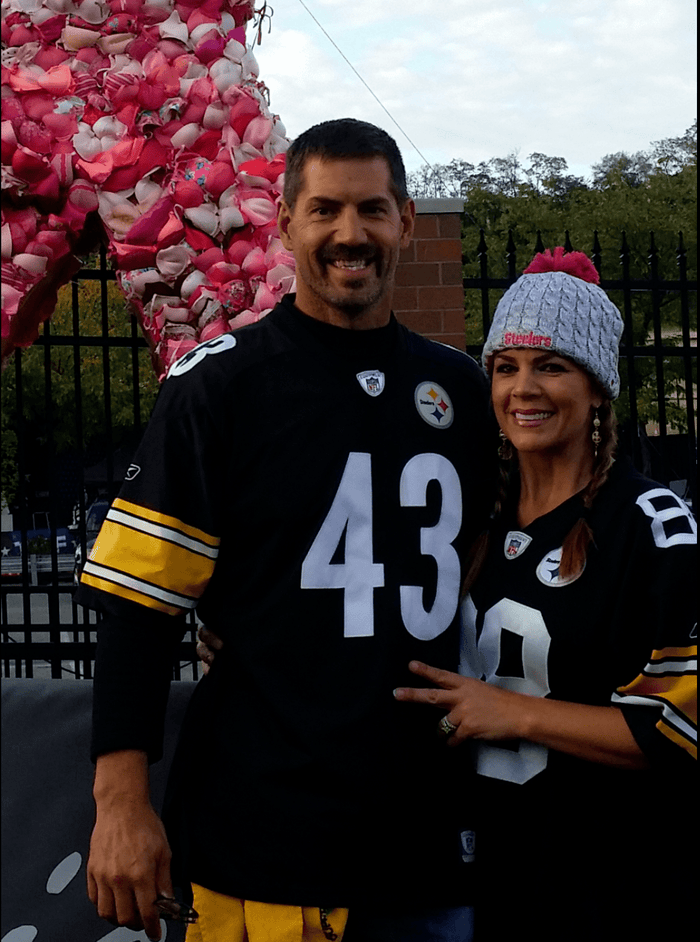 a man and a woman pose together in Pittsburg Stealers' jerseys. near the finish line of a marathon