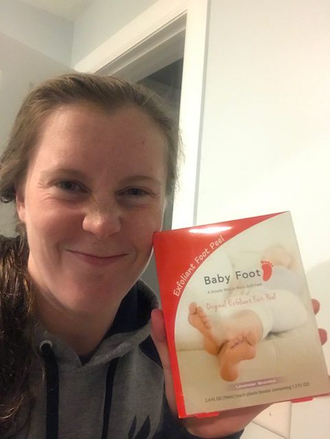 Cozad Magaña, olympic diver holds up Baby Foot peel packaging next to her face while she smiles