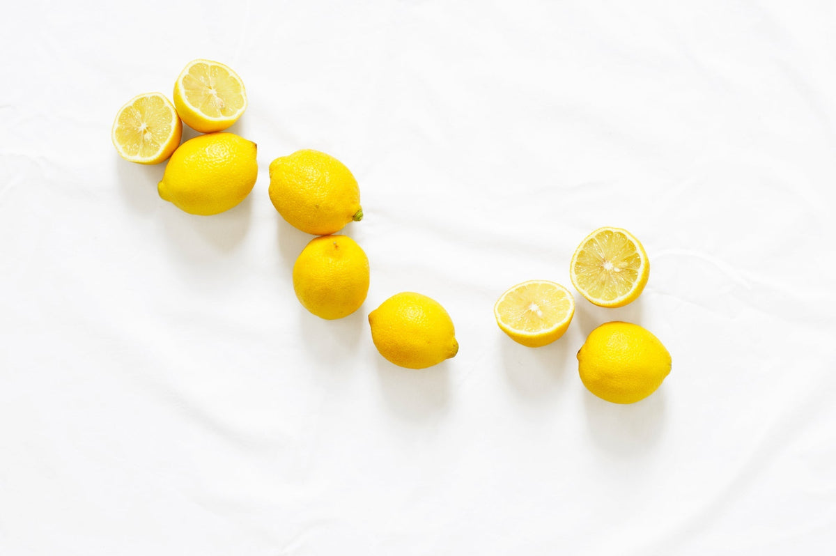 a top-down shot of several lemon halves and entire lemons on a white sheet